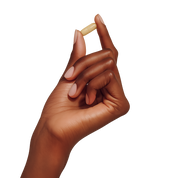Hand holding a small Seazenal supplement multivitamin capsule against a transparent background. 