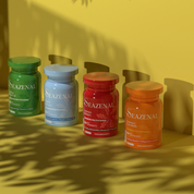 Four Seazenal supplement bottles on a yellow surface with leaf shadows. Seazenal Summer essentials capsule supplement orange bottle with label on an orange background. with ingredients including vitamin C, vitamin D3, magnesium, coenzyme q10, biotin, vitamin b12, iron, zinc, selenium, Chromium. Premium
