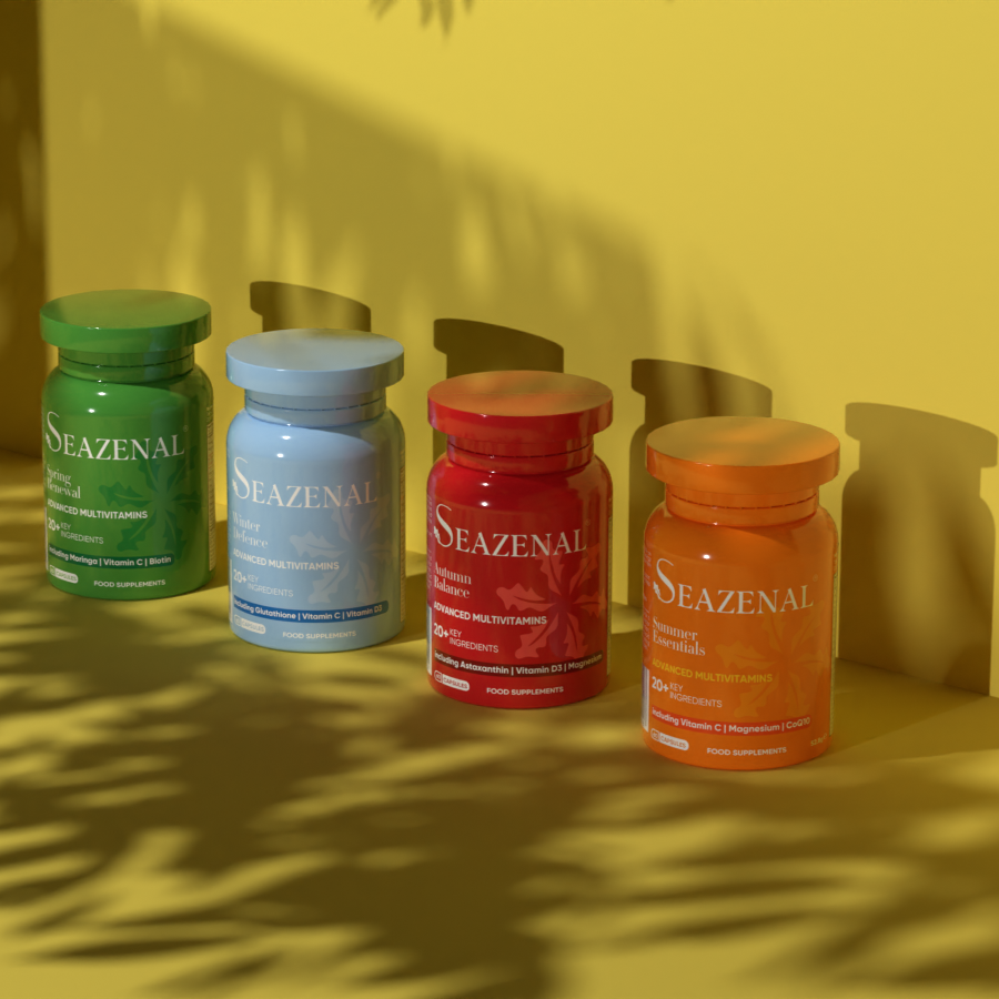 Four Seazenal supplement bottles on a yellow surface with leaf shadows. Seazenal Summer essentials capsule supplement orange bottle with label on an orange background. with ingredients including vitamin C, vitamin D3, magnesium, coenzyme q10, biotin, vitamin b12, iron, zinc, selenium, Chromium. Premium